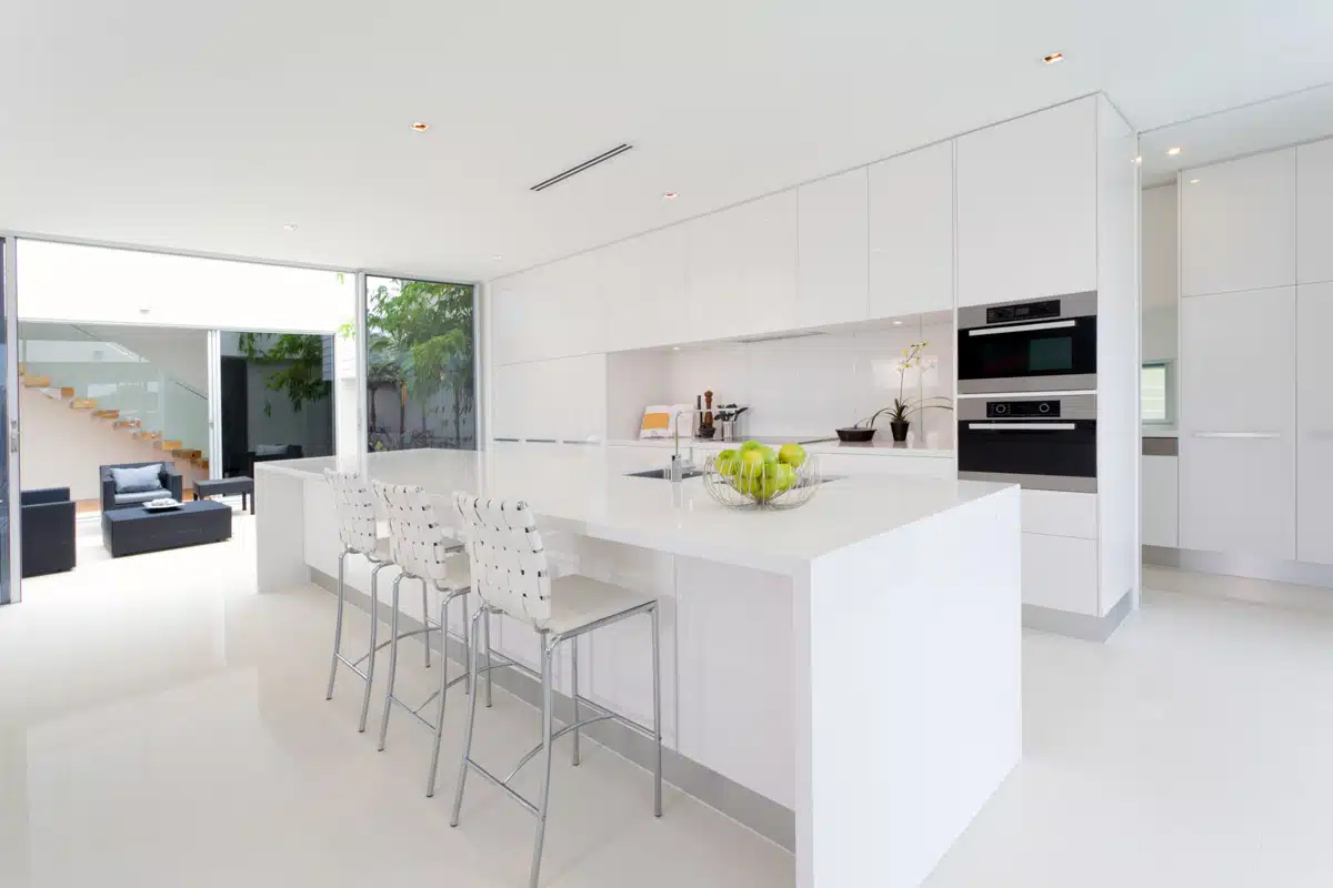 spacious kitchen with island stools and backsplash made of corian
