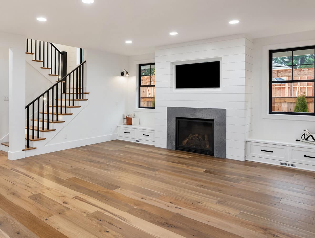 Contemporary living room with white paint, wood floor, shiplap wall, coved windows and fireplace