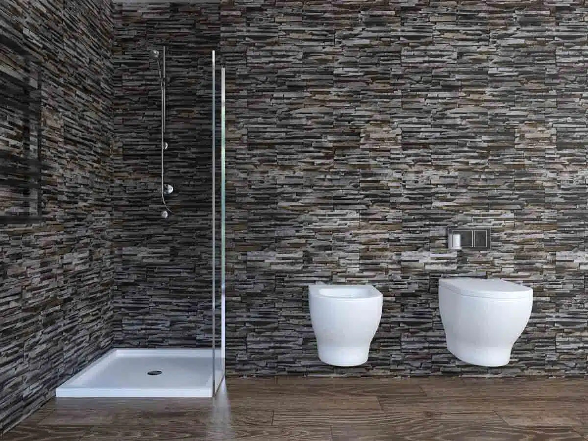 bathroom with stacked laid stone shower wall and toilet