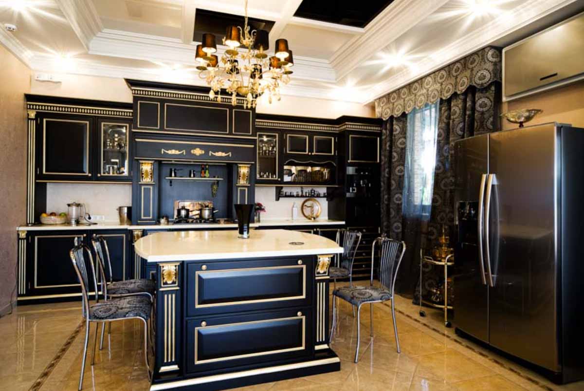 black kitchen with chandelier island table chairs cabinets refrigerator and curtains