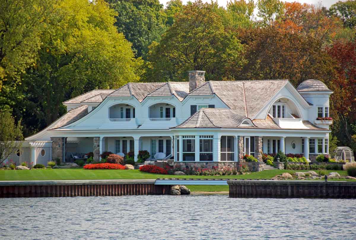 luxury house by the lake with dormer, chimney, and covered front porch