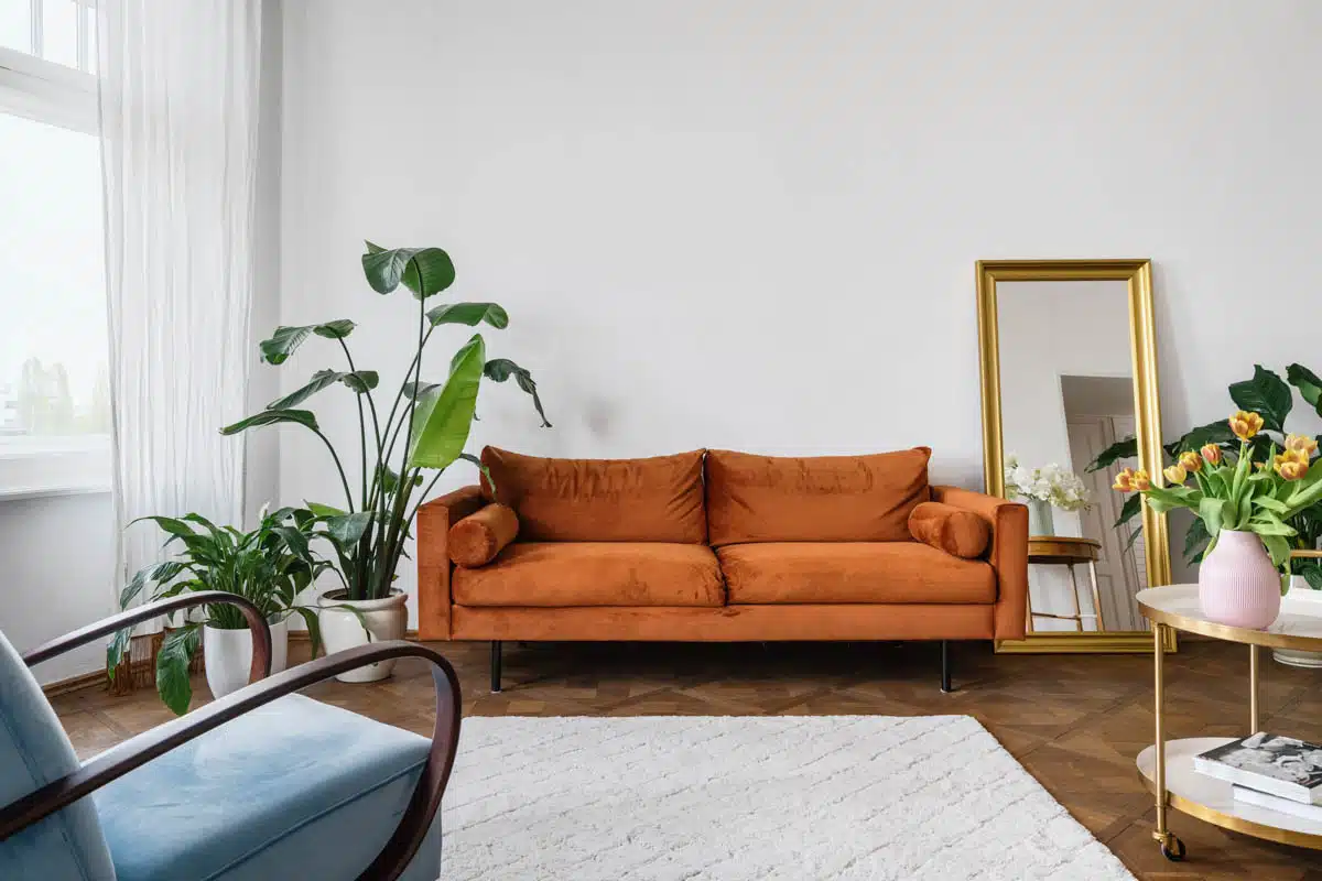 simple room with orange sofa mirror and windows