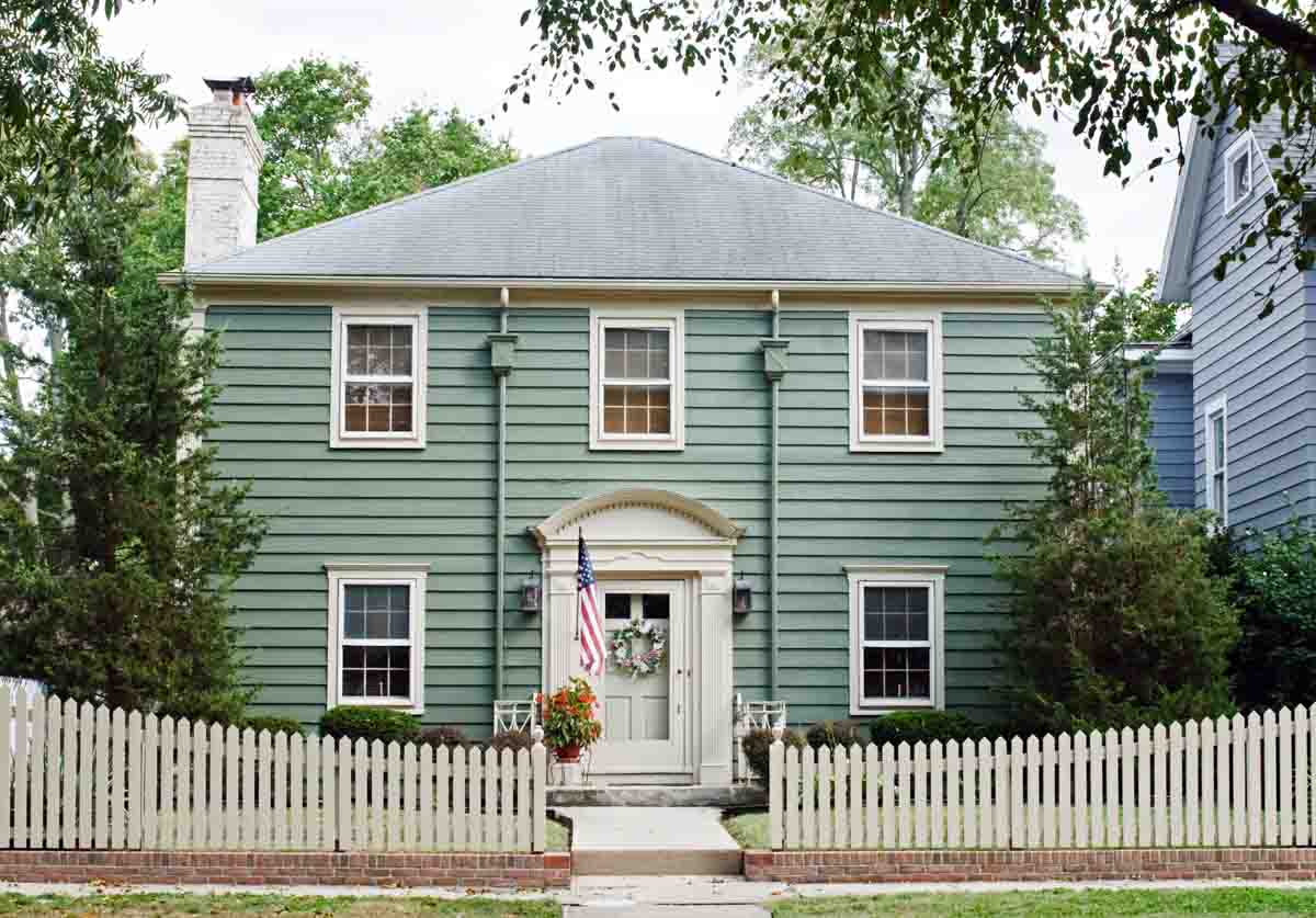 teal house with white door and white picket fence