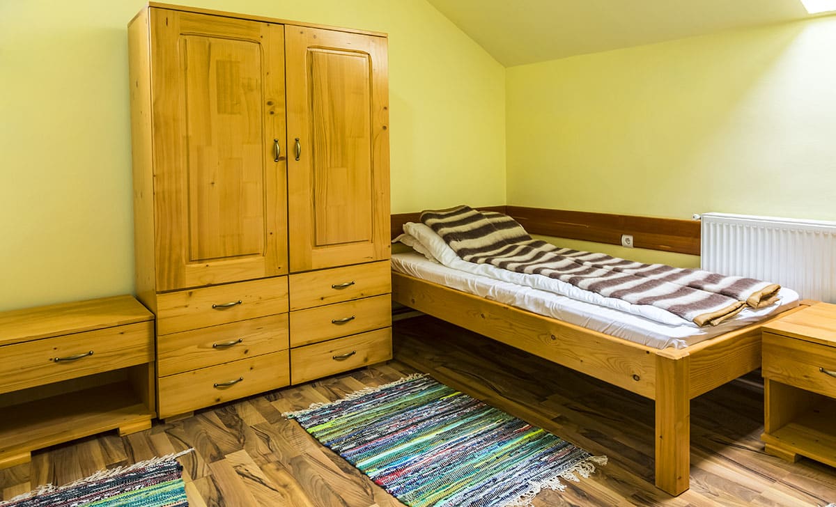 Small bedroom with small bed dresser, rugs and yellow paint