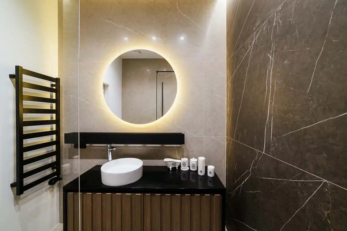 bathroom with round mirror sink and towel holder