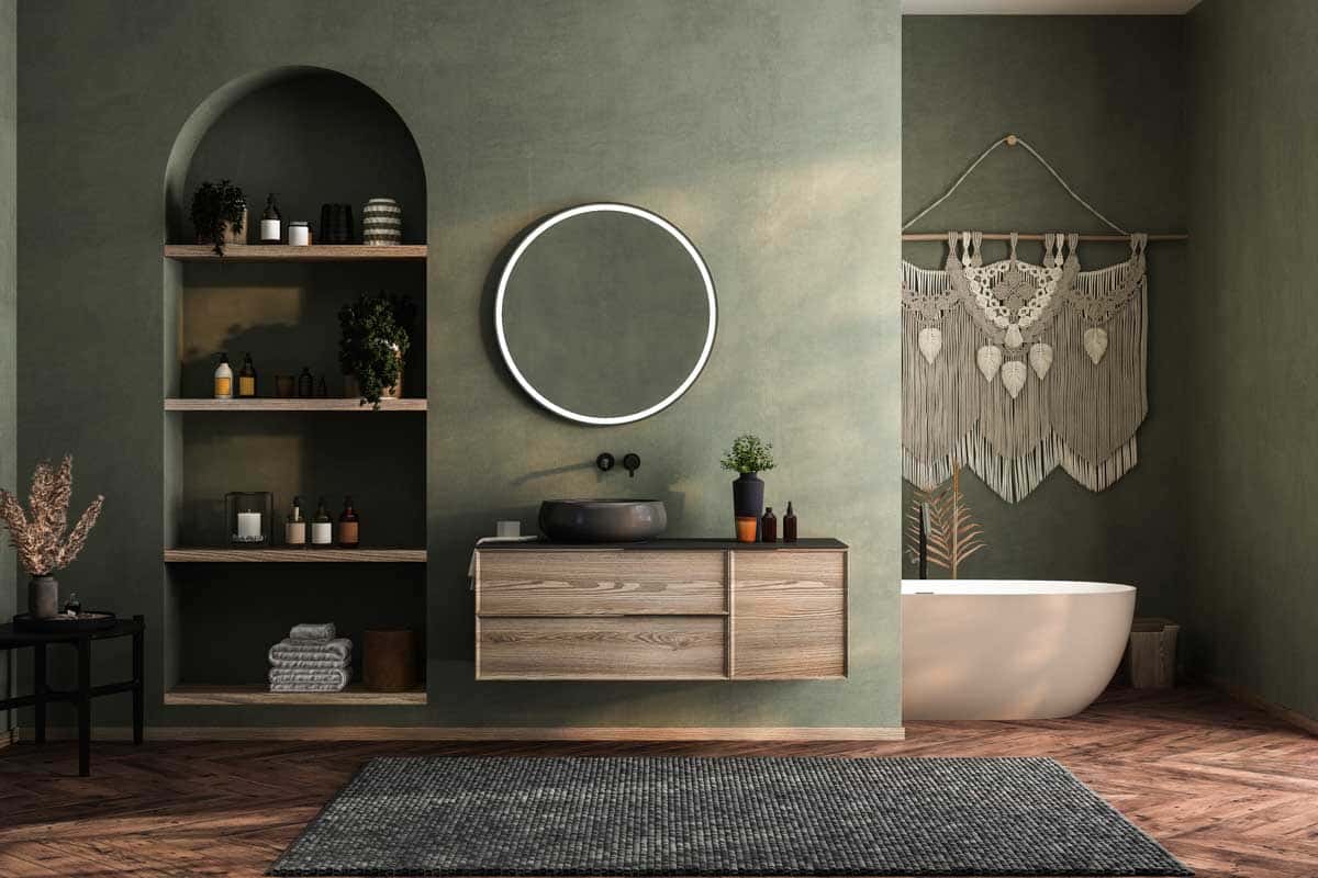 green bathroom with counter round mirror and shelves