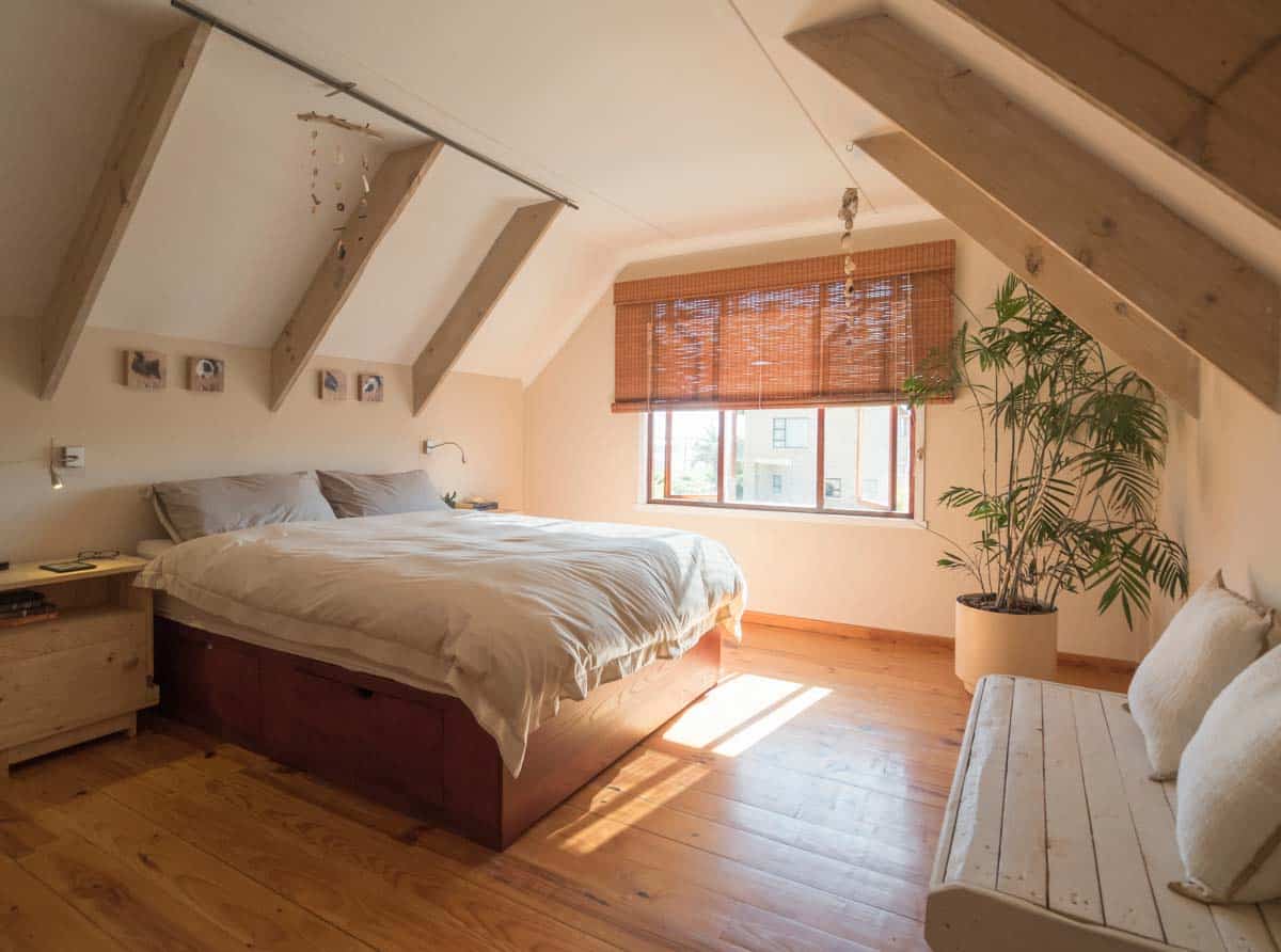 attic bedroom for guests with wood flooring and indoor plants