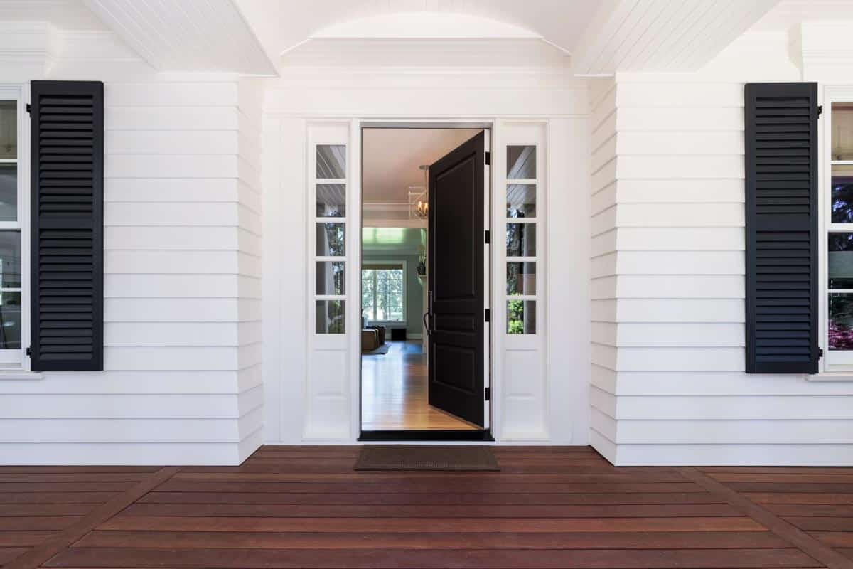 front porch with white shiplap wall and black door