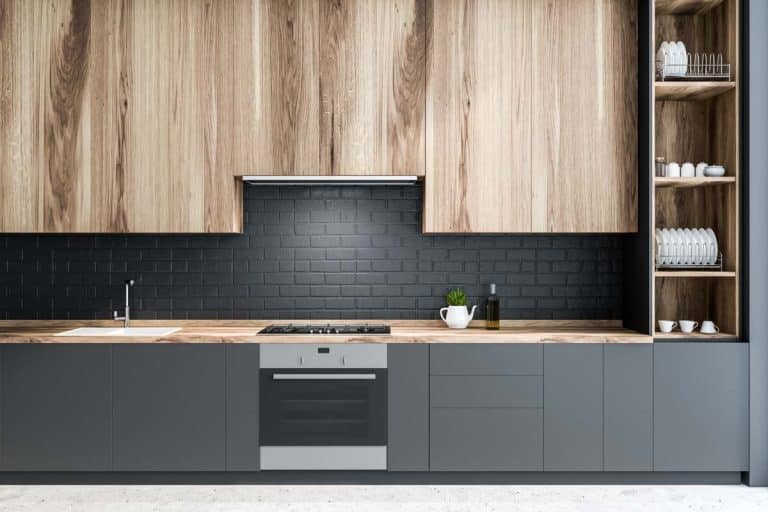 kitchen with black brick backsplash wood cabinets and stove