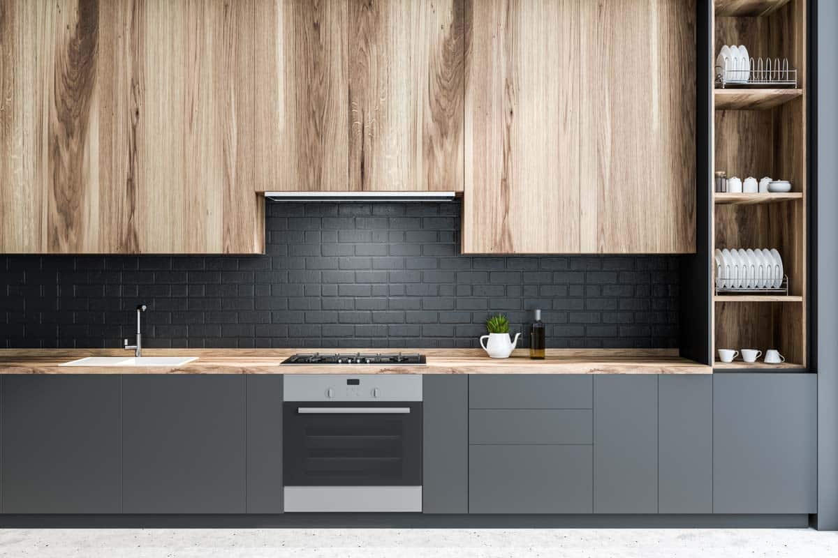 kitchen with black brick backsplash wood cabinets and stove