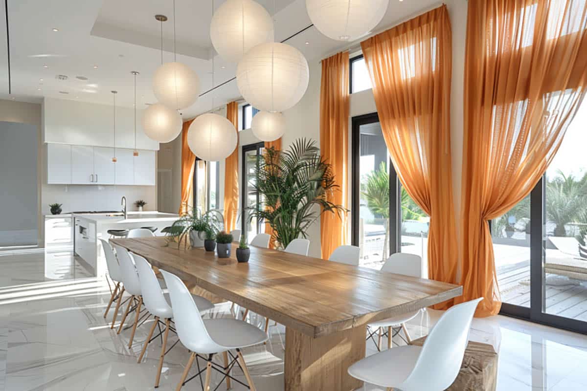 Contemporary dining room featuring sheer soft orange curtains, wood table and white chairs