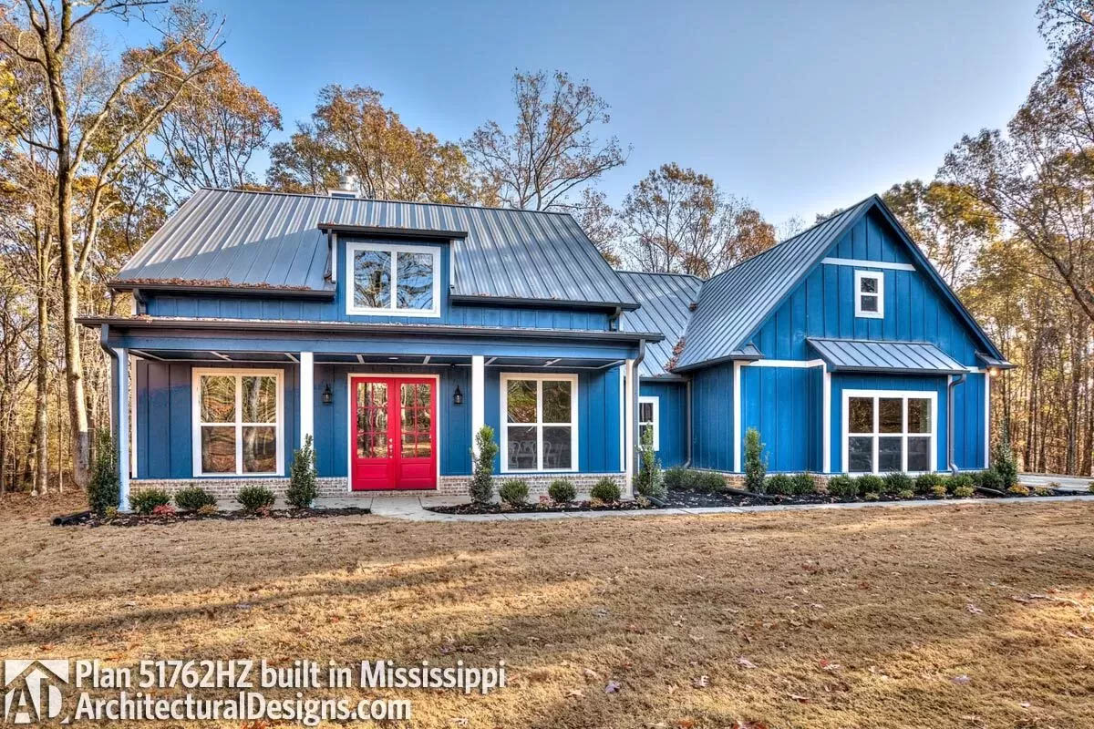 Blue painted board and batten home with metal roof and red front door