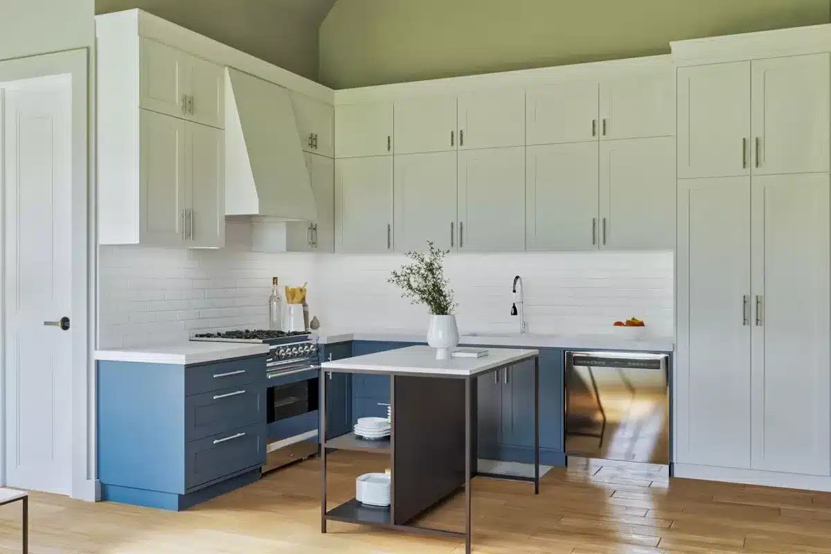 Studio kitchen with blue base cabinets and white uppers with portable island