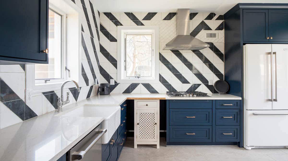 Art deco kitchen with geometric backsplash in black and white with navy tone cabinetry