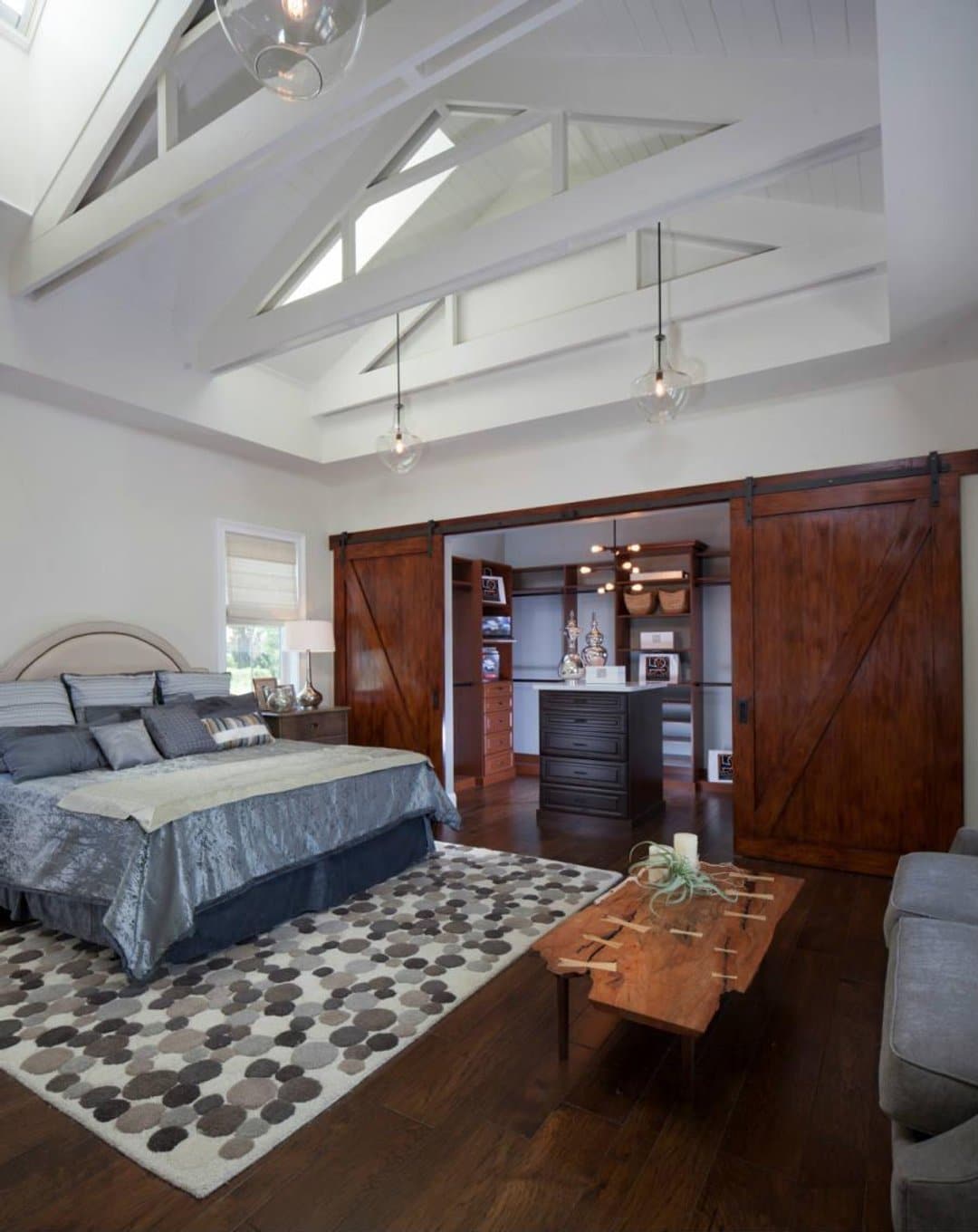 Beautiful bedroom with high beam ceiling, sliding barn doors to walk-in closet with island