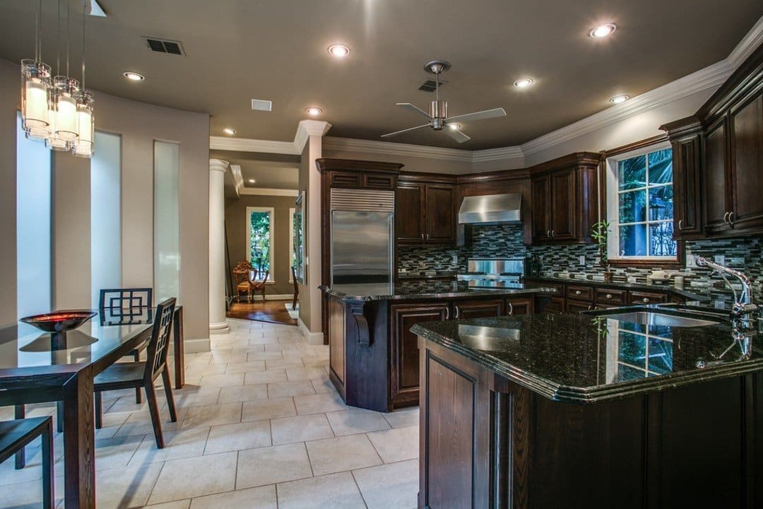 Kitchen with dark cabinets and black granite countertops with tile flooring and pendant over dining table