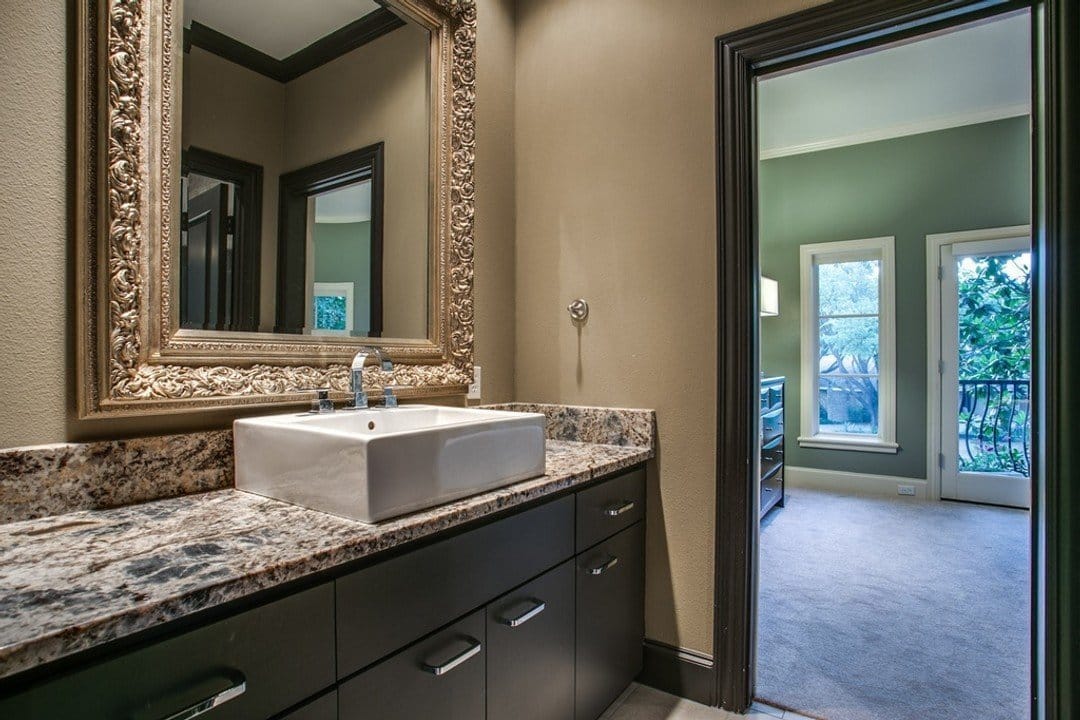 Bathroom vanity with granite countertops, basin sink and large gilded gold mirror