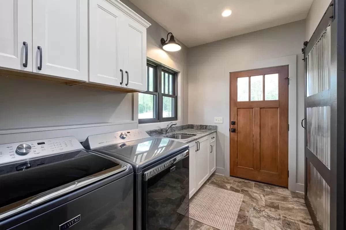 Narrow laundry room with tile floors and wall storage cabinets