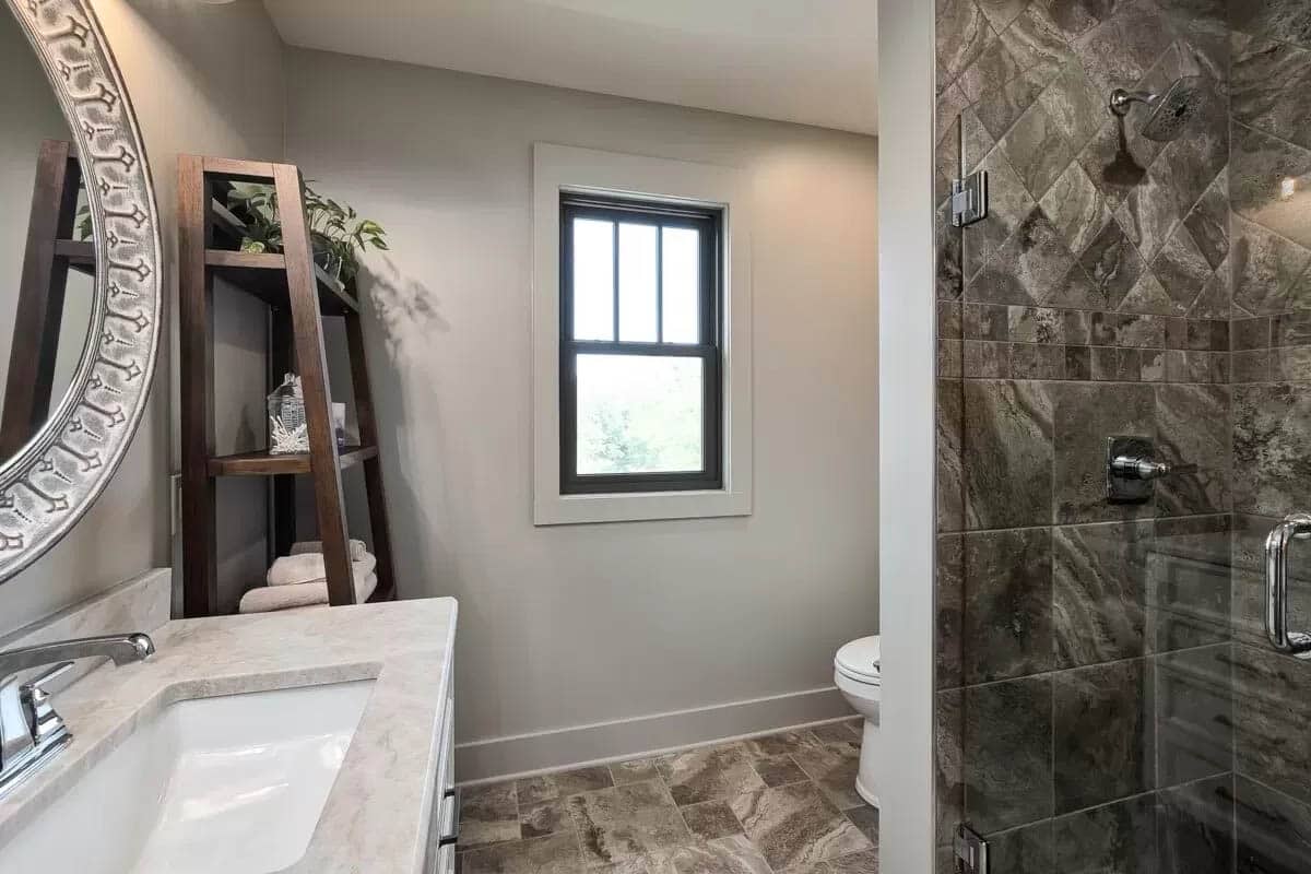 Stylish bathroom with round mirror dark tile shower