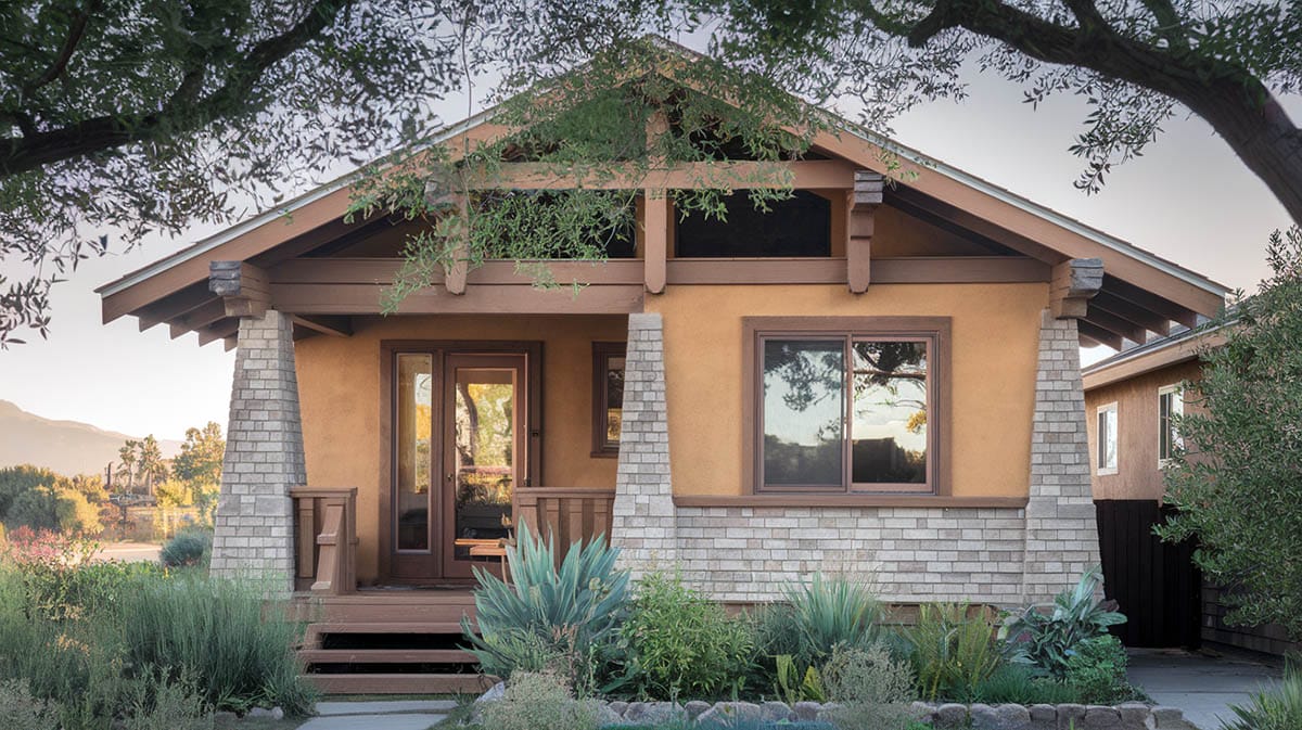 California bungalow with earth tones sloping roof wooden beams and wooden porch