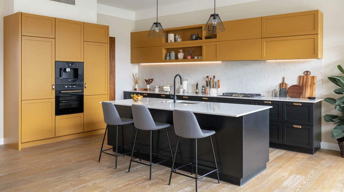 Contemporary kitchen with two tone upper mustard yellow cabinets black lower cabinets white quartz countertops with island