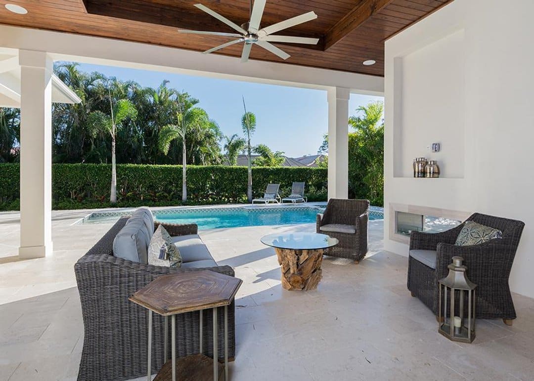 Covered patio with outdoor gas fireplace and view of pool