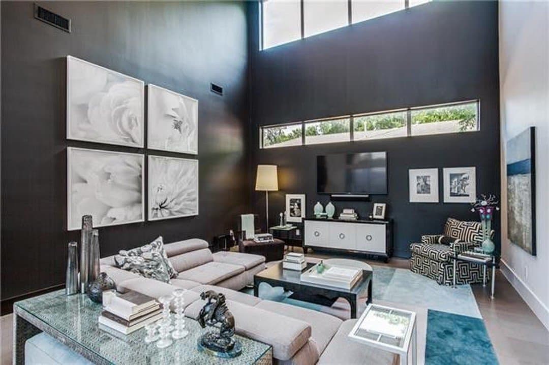 Dark themed modern living area with high ceiling and upper windows