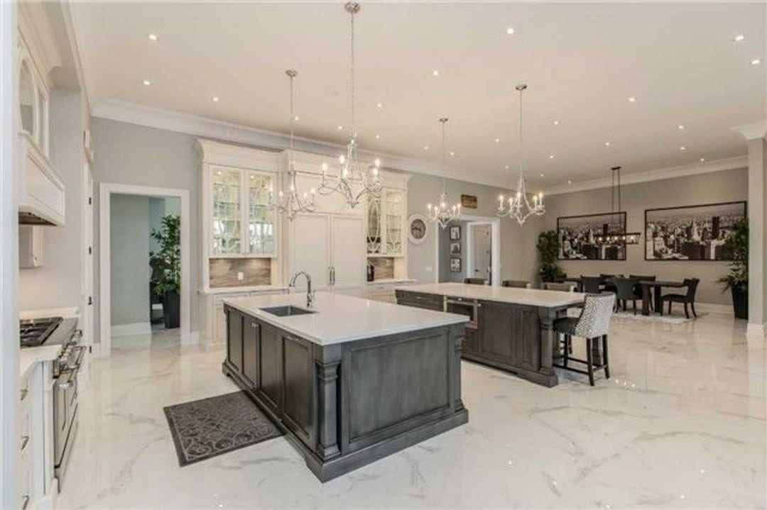 Double kitchen islands with four chandeliers and views to the dining room