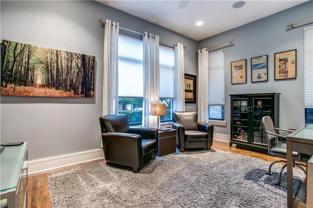 Home office with gray paint, plush leather armchairs and desk