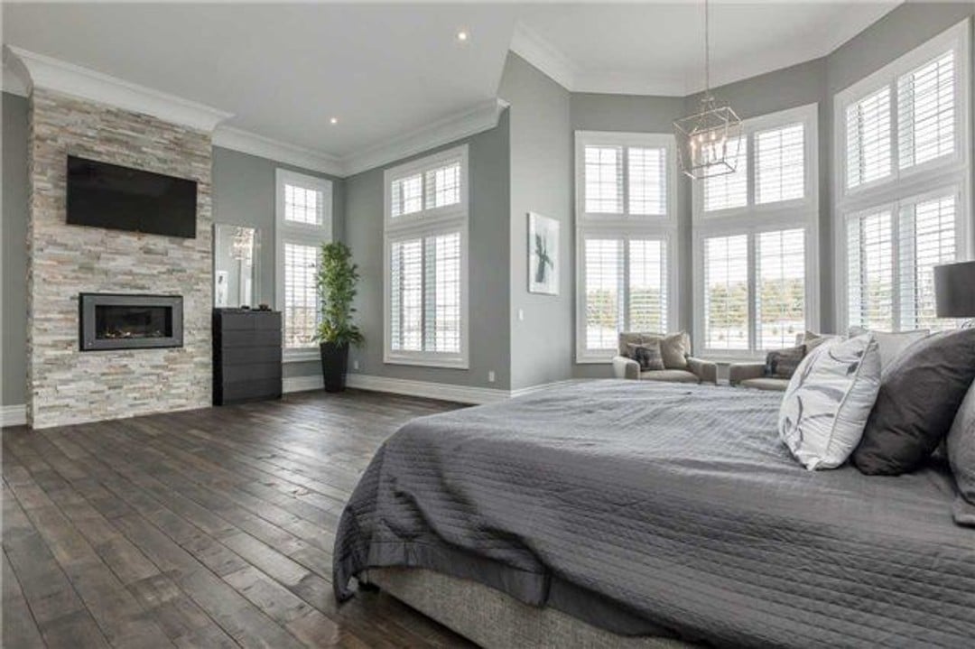 Spacious master bedroom suite with fireplace and wood plank flooring