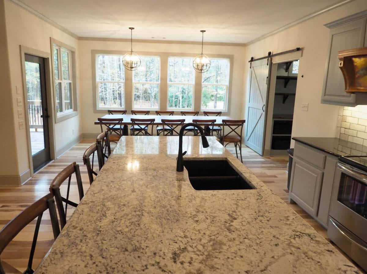 open concept kitchen with large granite island and dining room with globe chandeliers