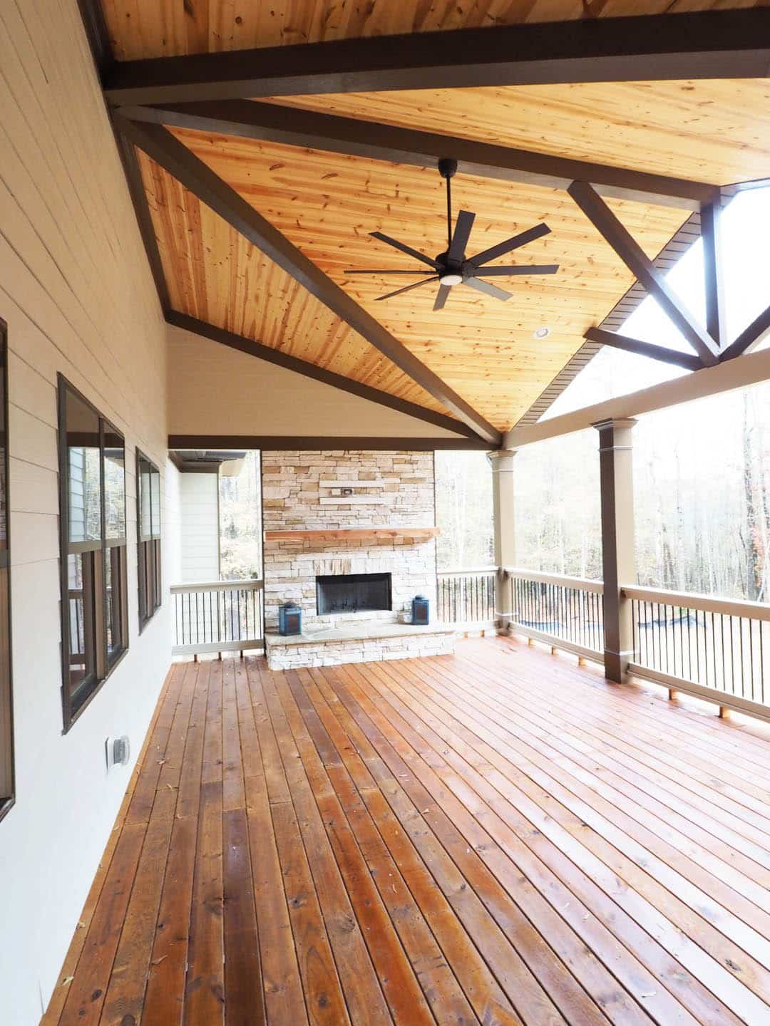 Outdoor covered terrace deck with fireplace gathering area and ceiling fan