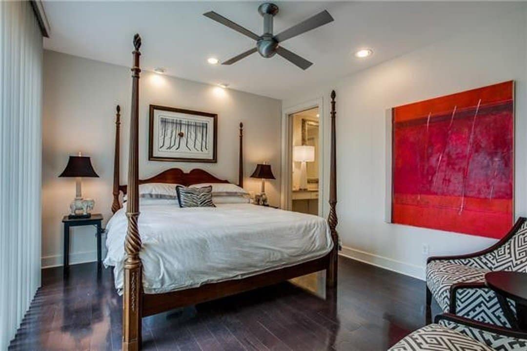 Light-filled bedroom with wood plank floors and four post bed