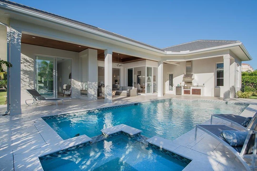 Geometric pool with hot tub and views of outdoor kitchen and covered patios