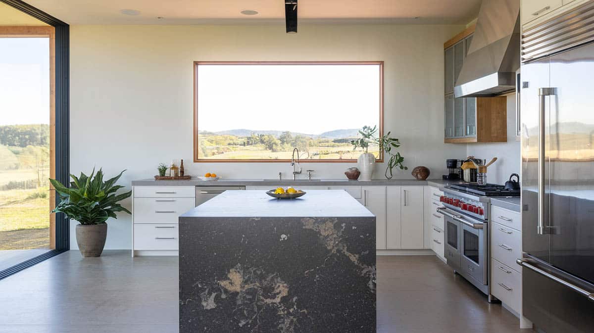 Modern kitchen with dark quartz countertop island and picture window with views