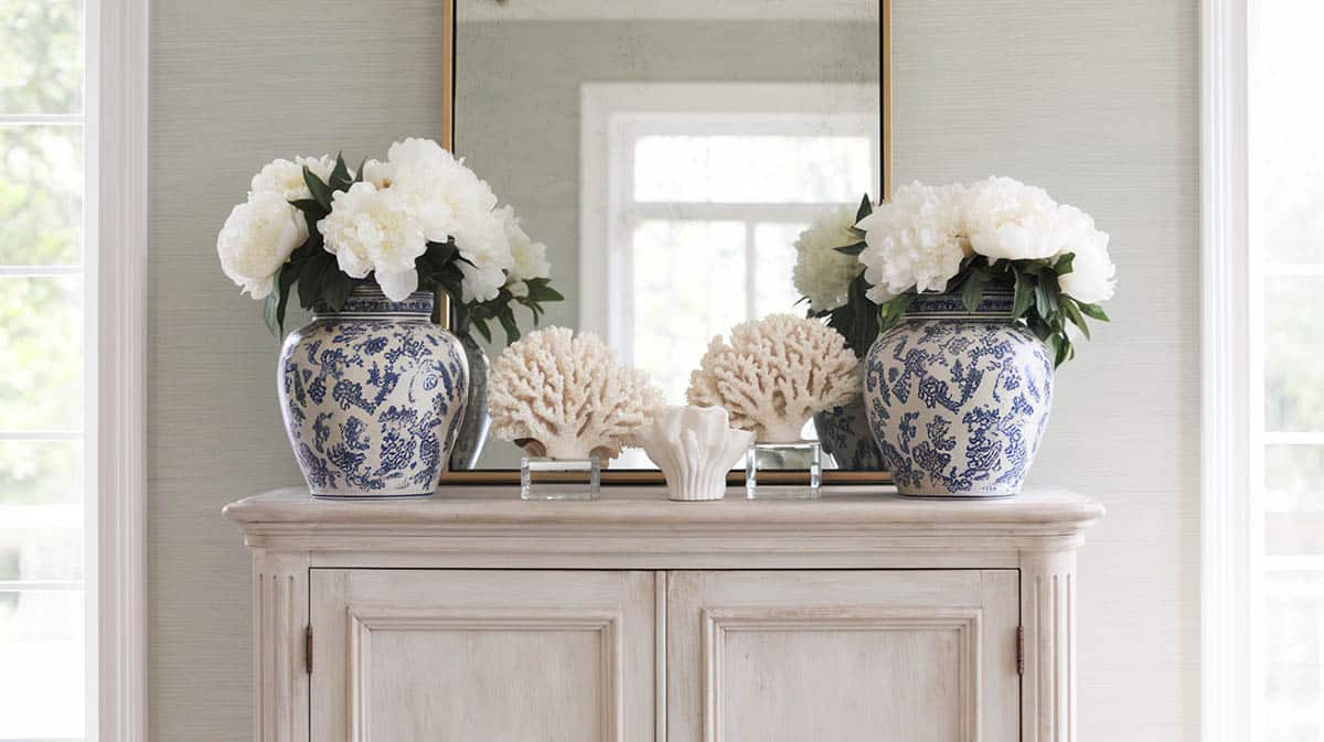 Whitewashed oak armoire with large blue and white ginger jars with flowers and coral 