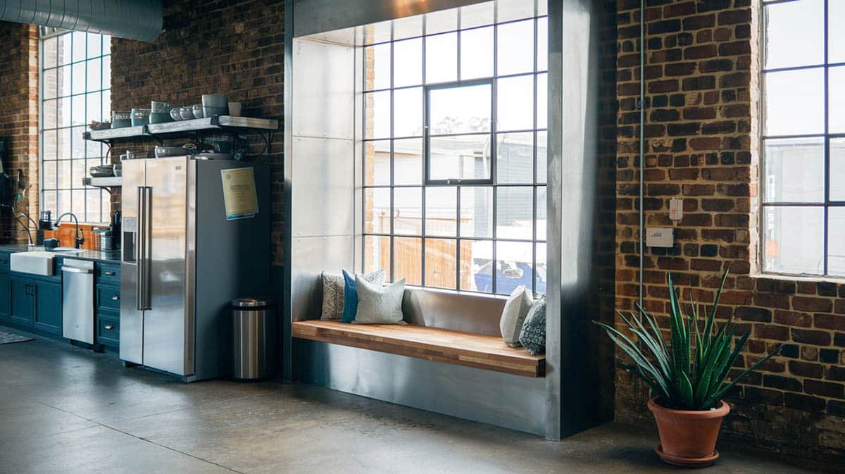 Industrial chic kitchen with metal framed seat, reclaimed wood bench top and warehouse style windows