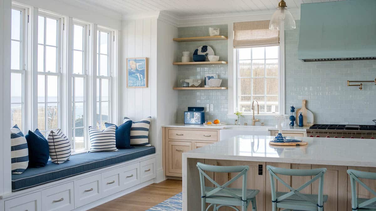 Coastal kitchen with light blue toned tile, nautical pillows and white wood for a beachy feel