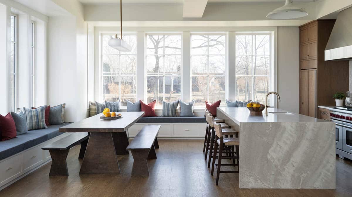 Kitchen with wrap-around seating and banquet table with waterfall island