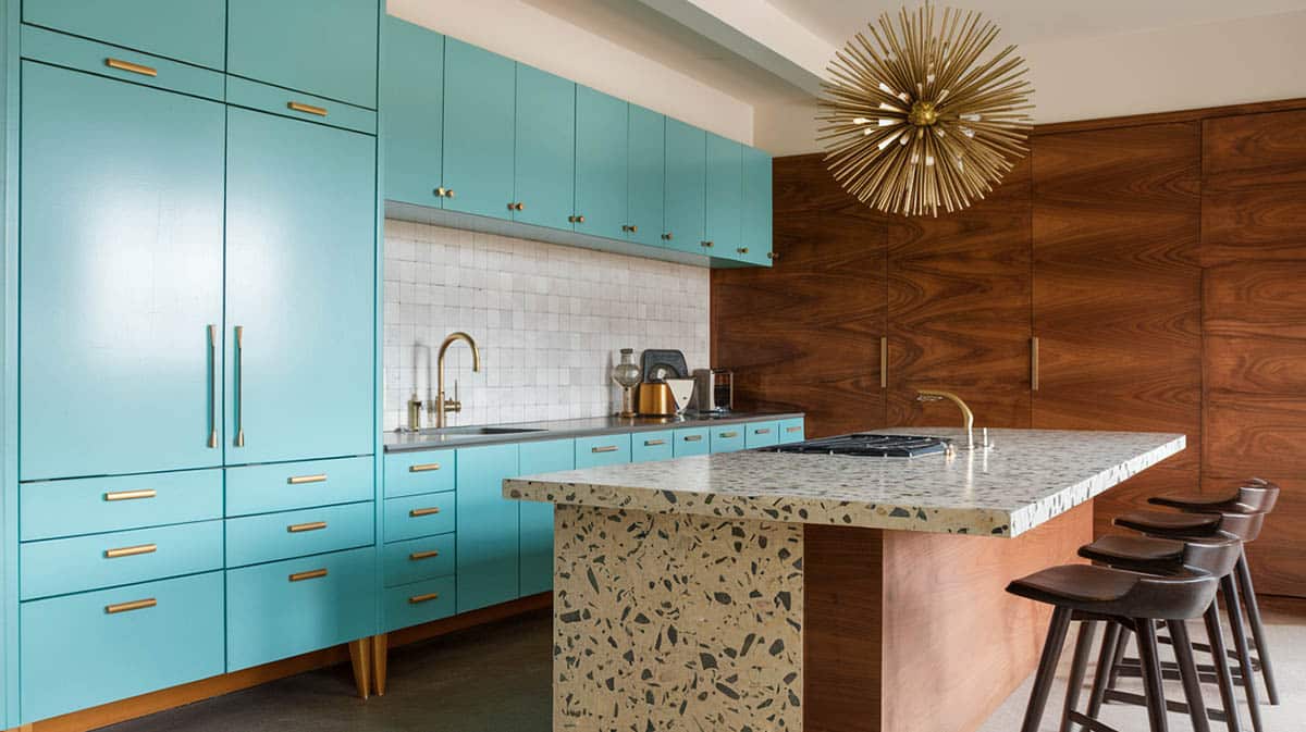 Mid century modern designed kitchen built with turquoise slab front cabinets with minimal brass pulls and geometric terrazzo island top