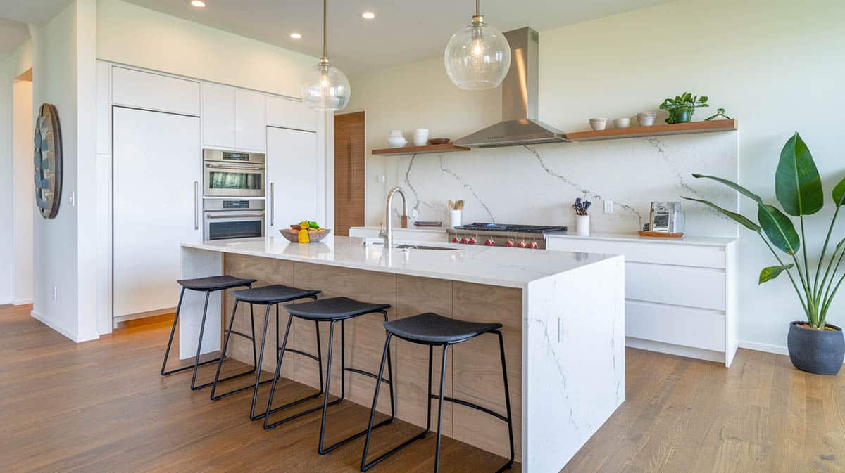 Contemporary kitchen with white quartz countertop island and black bar stools white cabinetry