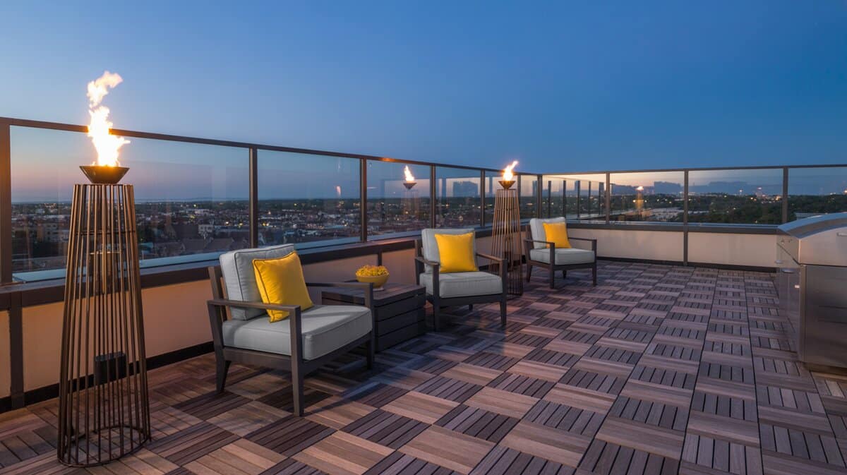 Rooftop terrace with modular wood deck tiles, gray armchairs with yellow pillows and tall fire torches